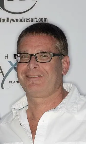 A man with glasses and short hair wearing white shirt.